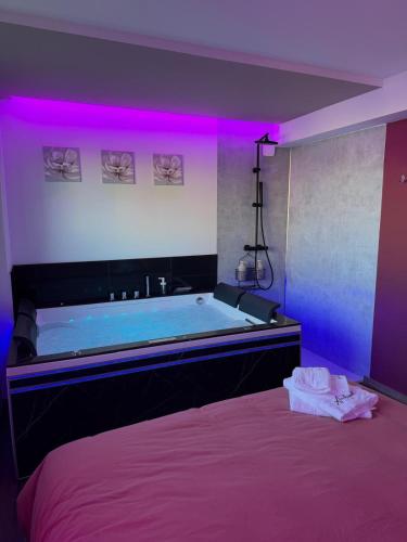 a bedroom with a tub with a purple lighting at L'écrin - Studio Cosy et Lumineux in Andance