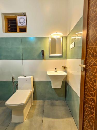 a bathroom with a toilet and a sink at Mamoksha Riverdale in Padinjarathara