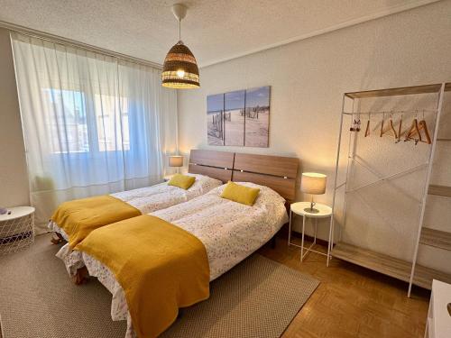 a bedroom with a large bed with a yellow blanket at Villa Yoli, céntrico con plaza de garaje in Avilés