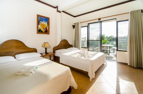 a hotel room with two beds and a balcony at Turtle Inn Resort in Boracay