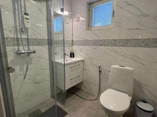 a white bathroom with a shower and a toilet at Lake Suite Family in Lahti