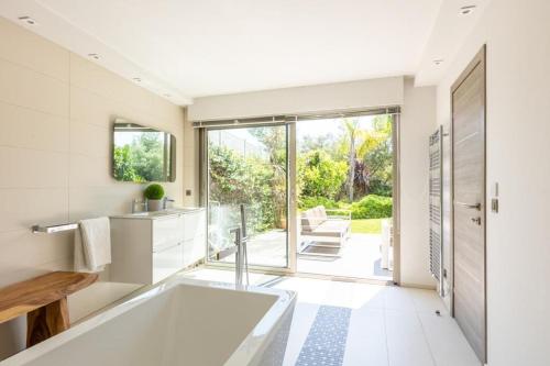 a bathroom with a white tub and a large window at FRGK Luxury Two-Storey Villa with Pool & Rooftop Peaceful Setting Lord Brougham in Cannes
