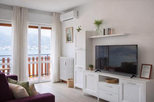 a living room with a flat screen tv on a white entertainment center at Lake Como Lilla Apartment in Oliveto Lario