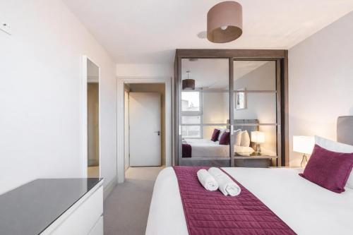 a bedroom with a large white bed with purple sheets at Roomspace Serviced Apartments - The Quadrant in Richmond upon Thames