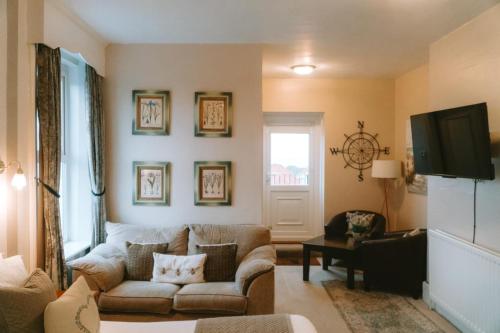 a living room with a couch and a tv at The White House Inn - Whitby in Whitby