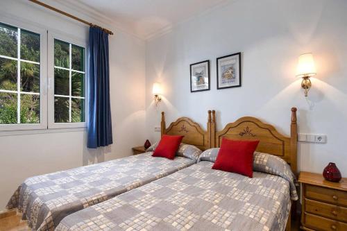 a bedroom with a bed with two red pillows at Villa Manuel by Villa Plus in Son Parc