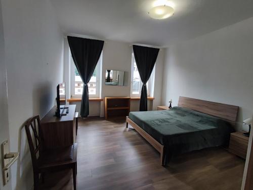 a bedroom with a bed and a desk and two windows at La Strada di Tiziano in Pieve di Cadore