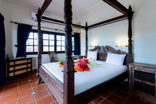 a bedroom with a four poster bed with flowers on it at Villa Landhuis 6 - Coral Estate in Willibrordus