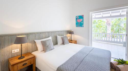 a bedroom with a large bed and a balcony at Villa Ocho 8 - Coral Estate in Willibrordus