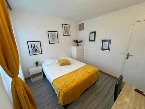a bedroom with a bed with a yellow blanket on it at Les Trois koush in Courcouronnes