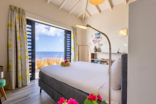 a bedroom with a bed with a view of the ocean at Villa Esmeraldas 1207 - Coral Estate in Willibrordus