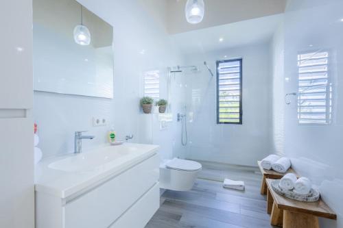 a white bathroom with a tub and a toilet and a sink at Villa Esmeraldas 1207 - Coral Estate in Willibrordus
