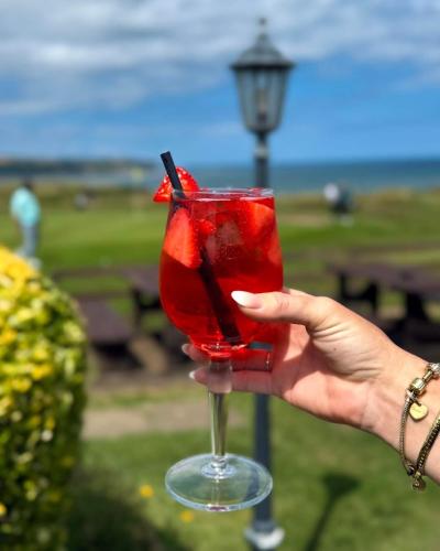 a hand holding a red drink in a glass at The White House Inn - Whitby in Whitby