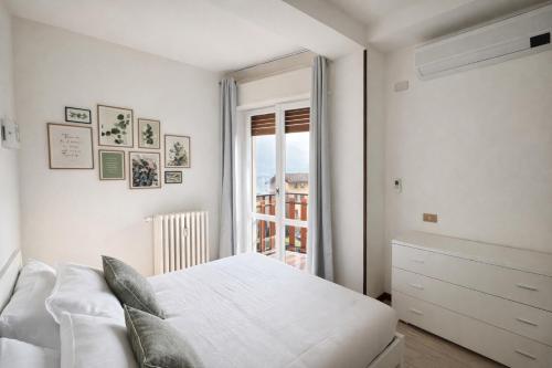 a white bedroom with a bed and a window at Lake Como Lilla Apartment in Oliveto Lario