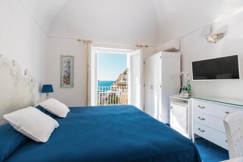 a bedroom with a blue bed with a view of the ocean at Villa La Tartana in Positano