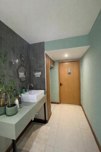 ein Badezimmer mit Waschbecken und Holztür in der Unterkunft HMG Rio Suítes in Rio de Janeiro