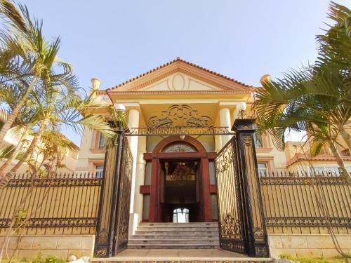 a building with a gate and palm trees at قصر فنيسيا 6غرف للإيجار ViP Vienice Palace luxury in 6th Of October