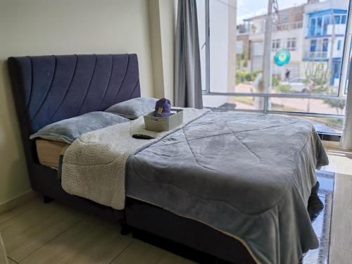 a bedroom with a bed with a blanket and a window at Apartamento familiar en zona norte de Tunja, cerca a Viva, con parking in Tunja