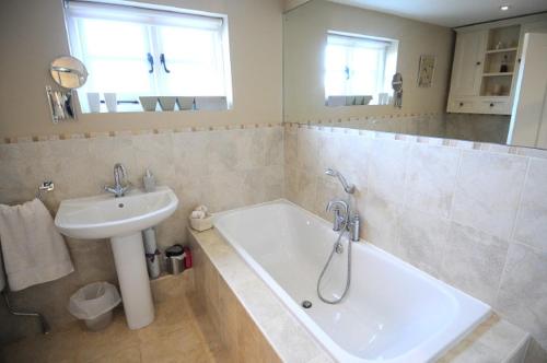 a bathroom with a sink and a bath tub next to a white sink at Blackbrook House in Holmwood