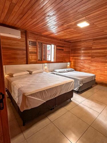 two beds in a room with wooden walls at Vale dos Imigrantes in Bento Gonçalves