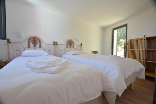two beds in a bedroom with white sheets at Casinha in Sintra