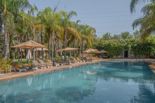 a large swimming pool with chairs and umbrellas at Palais Mirage d'Atlas, Hôtel & Spa in Marrakesh