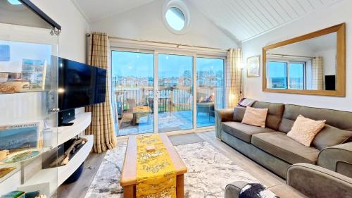 a living room with a couch and a tv at Low Lake Lodge - Lakeside - Part of the The Bay Filey Holiday Village with pool, gym and direct beach access, pub, restaurant, tennis and meadows walks in Reighton