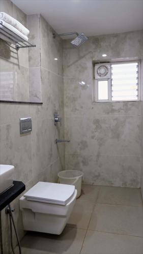 a bathroom with a toilet and a sink and a window at Rams Inn in Krishnagiri
