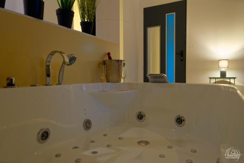 a bath tub with a sink in a bathroom at Le Cocon Love Room & Spa in Nancy