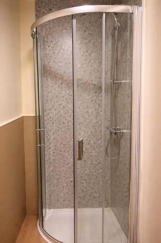 a shower with a glass door in a bathroom at Saféra Dewsbury Westpark in Batley Carr