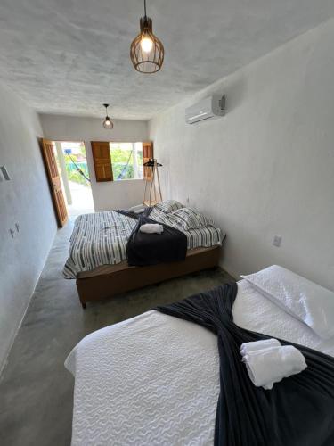 a bedroom with two beds and a window at Suíte Adam 1 em Caraíva com piscina 900m da Vila in Caraíva