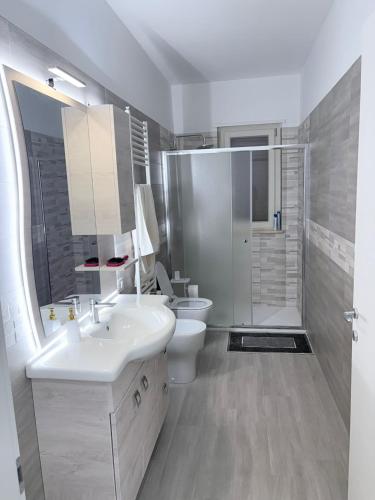 a white bathroom with a sink and a toilet at Oltre Le Onde in Nova Siri Marina