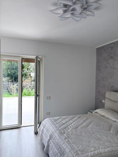 a white bedroom with a bed and a sliding glass door at Oltre Le Onde in Nova Siri Marina
