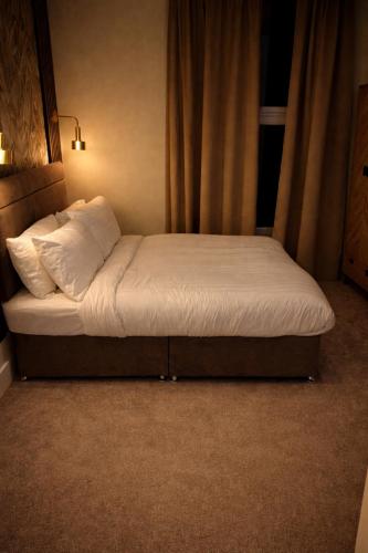 a bed with white sheets and pillows in a room at Saféra Dewsbury Westpark in Batley Carr