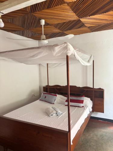 a bedroom with a canopy bed with a wooden ceiling at Maison Baby plein centre in Ambatoloaka