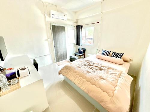 a white bedroom with a bed and a desk at อมรรัตน์Room in Pathum Thani