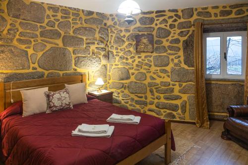 a stone walled bedroom with a bed with towels on it at Casa da Ramada in Campo do Gerês