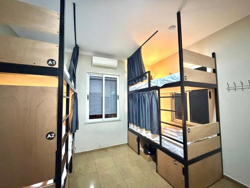 una stanza con tre letti a castello e una finestra di PMG Hostel a Tirana