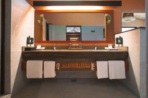 a bathroom with a sink and a large mirror at Sekenani,Leparan Lodge in Narok