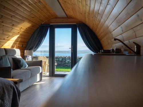 a living room with a couch and a large window at Bayview Glamping Pods Kerry in Ballyheigue