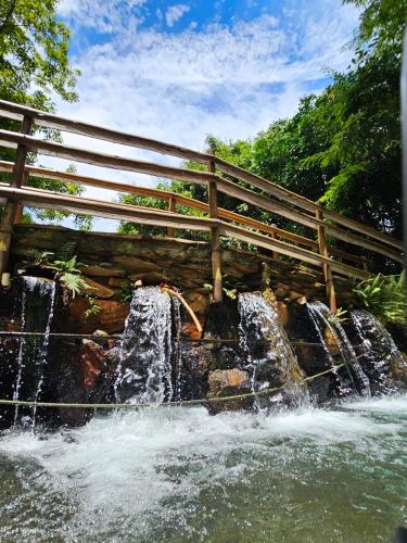a waterfall with a wooden bridge over a river at Thermas Paradise Residence in Rio Quente