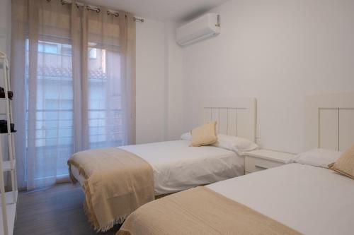 a white room with two beds and a window at Piso Moredas in Dúrcal