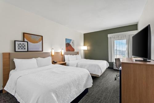 a hotel room with two beds and a flat screen tv at Spark by Hilton Bardstown in Bardstown