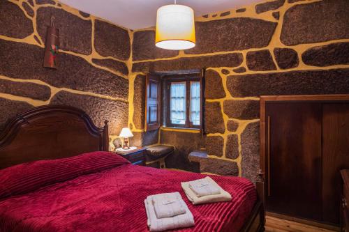 a bedroom with a red bed in a stone wall at Casa da Eira in Campo do Gerês