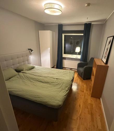 a bedroom with a bed and a chair and a window at Central accommodation in Umeå