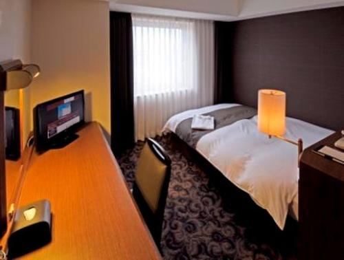 春日井市にあるホテルプラザ勝川のベッド、デスク、コンピュータが備わるホテルルームです。