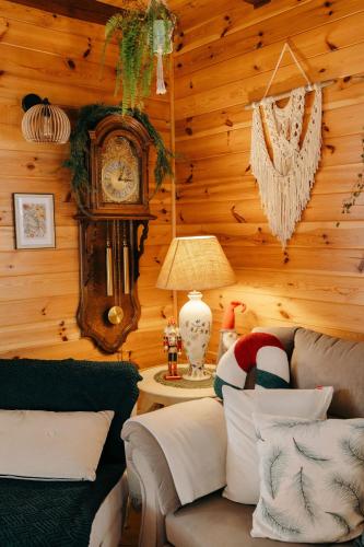 a living room with a couch and a grandfather clock at Dom Zielarki na Kaszubach - widok na jezioro, sauna, balia in Żuromino