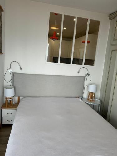 a bed in a bedroom with two lamps and a mirror at Cabourg Face A La Mer in Cabourg