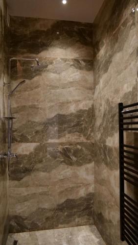 a bathroom with a stone wall with a shower at Nord Boutique Hotel by HORIZONT in Shkodër