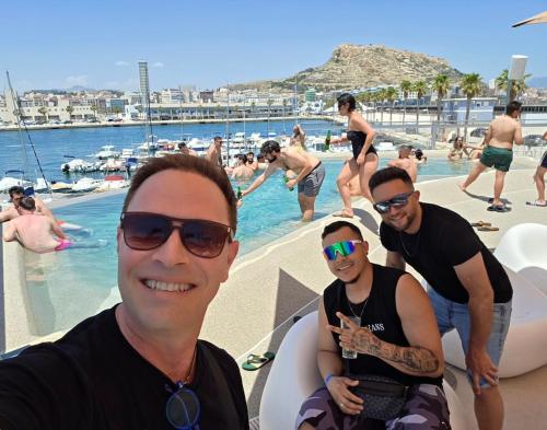 a group of men standing around a swimming pool at Postiguet Beach 2 garajes SuperHost SuperFlat in Alicante